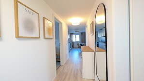 A hallway with framed artwork, a mirror, and a view into a dining area and kitchen. - Berth 6 - close to the beach and modern (Timmendorfer Strand)