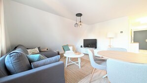 A modern living room with a sofa, a dining table, and a TV. - Berth 6 - close to the beach and modern (Timmendorfer Strand)