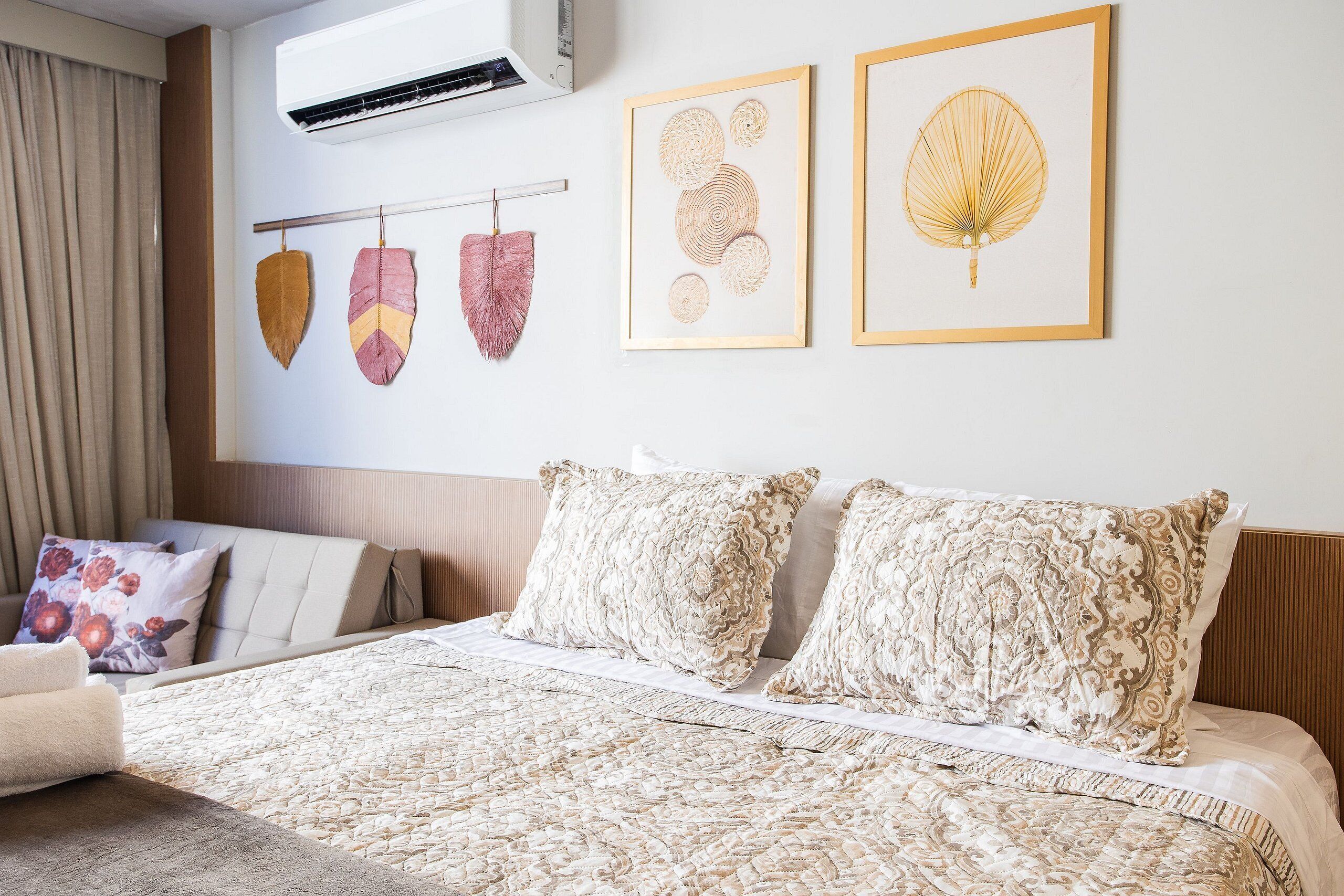 Habitación de hotel ordenada con una cama, dos almohadas, cabecero y una obra de arte en la pared.