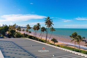 Eine Dachterrasse mit Blick auf Strand, Palmen und Stadtpanorama.