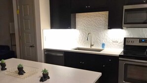 A modern kitchen with dark cabinets, a white countertop, a stainless steel oven, and a microwave. - Luxury 2 bedroom with two baths Pool Gym (Frisco)