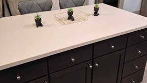 A kitchen with a white countertop, black cabinets, and two chairs. - Luxury 2 bedroom with two baths Pool Gym (Frisco)