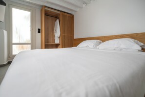 Een slaapkamer met een groot bed, een houten hoofdbord en een garderobe met schuifdeur.