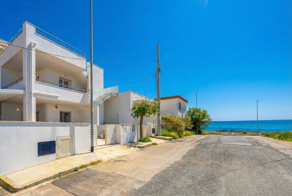 A coastal residential area with white buildings, a clear blue sky, and a view of the sea. - Apartment '3' with Air Conditioning (Torre San Giovanni)