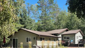 A two-story house with a stone foundation, a covered patio, and a fenced yard. - Peaceful 3-bedroom cabin with AC in charming Danbury with Lake 26 access (Danbury)
