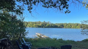 A lakeside view with a dock and chairs facing the water. - Peaceful 3-bedroom cabin with AC in charming Danbury with Lake 26 access (Danbury)