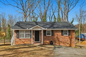 A single-story brick house with a gabled roof, a front porch, and a visible front door. - 3BR Retreat w/ 3 Queens Near Converse + Downtown (Spartanburg)