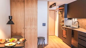 Een moderne keuken met houten kastjes, een eethoek met een tafel voor twee personen, en een klein krukje.