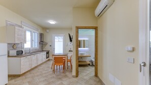 Une cuisine moderne avec des meubles blancs, un four à micro-ondes et un coin repas équipé de chaises.