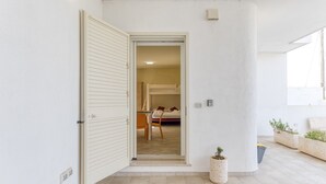Une pièce comprenant un lit, une chaise, une petite table et une plante en pot.