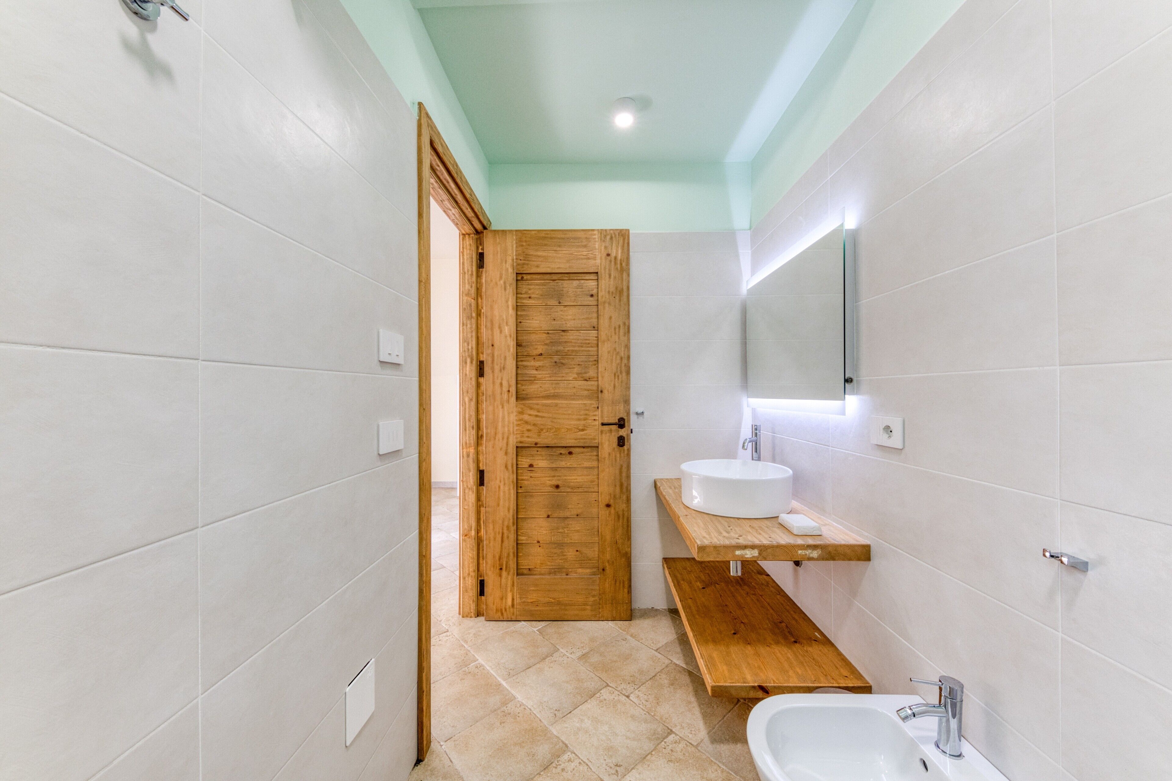 Een badkamer met een houten deur, een wastafel, een spiegel en een toilet.