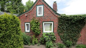 A brick house with three windows, ivy on the walls, and a small garden area. - Appartement in Spekendorf mit Terrasse by Interhome (Aurich)