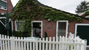 A brick house with a white picket fence, a green door, and a small table with a chair outside. - Appartement in Spekendorf mit Terrasse by Interhome (Aurich)
