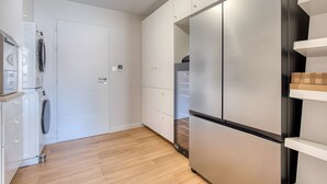 A modern kitchen with a stainless steel refrigerator, built-in oven, and white cabinetry. - La Villa des Pins d'Or – Family Villa with Pool and Spa in a Peaceful Natural Setting (La Tranche-sur-Mer)