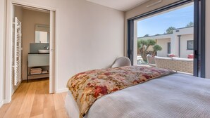 A bedroom with a large bed, a wardrobe, a mirror, and a view of the outside. - La Villa des Pins d'Or – Family Villa with Pool and Spa in a Peaceful Natural Setting (La Tranche-sur-Mer)