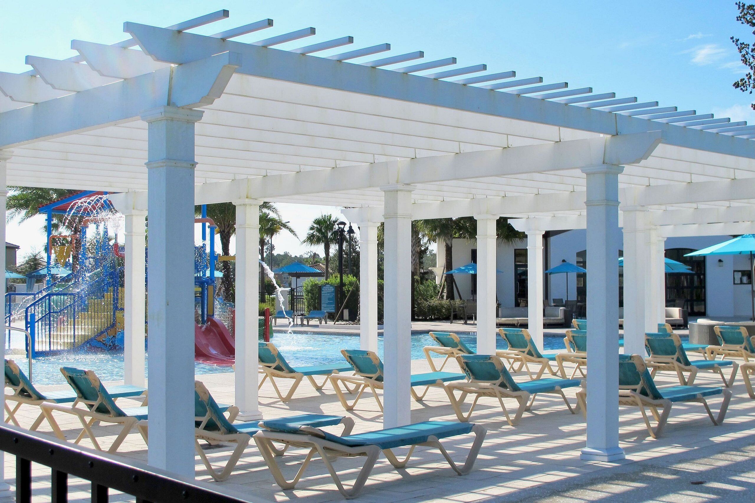 A covered pool area with lounge chairs and a water play structure.