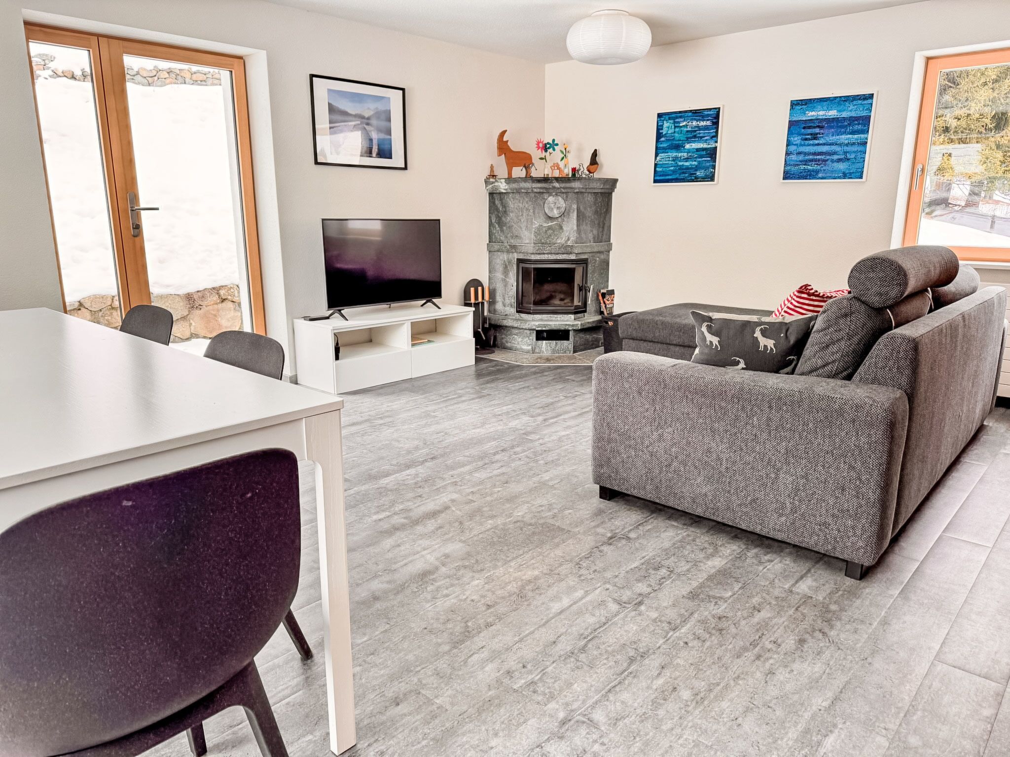 A modern living room with a fireplace, a flat-screen TV, a sofa, and a dining area.