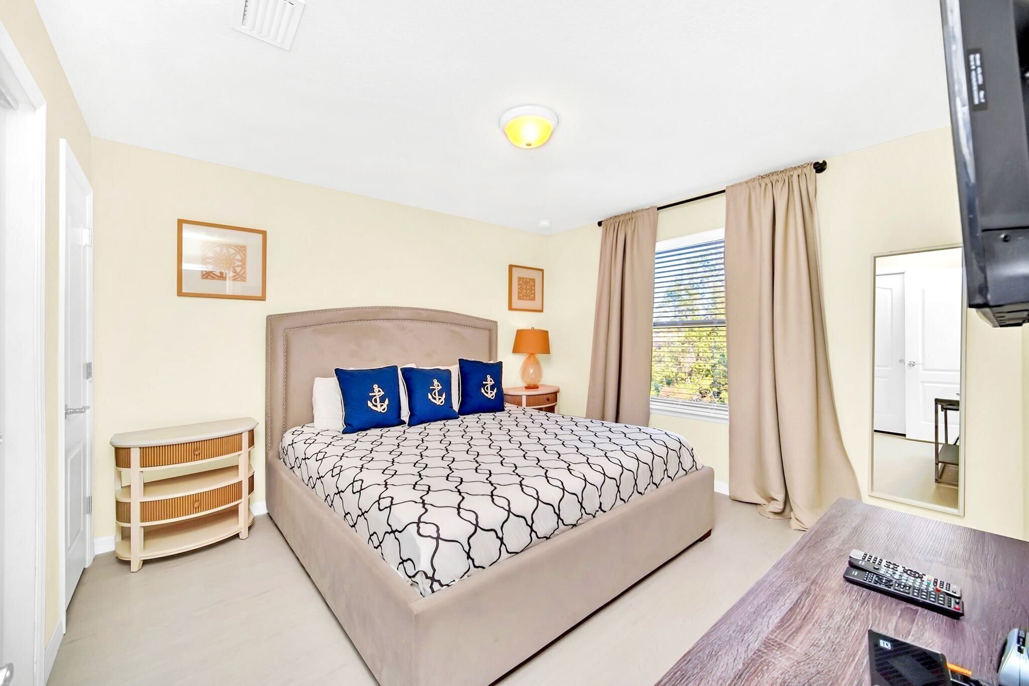 Une chambre d’hôtel avec un lit, une table de chevet, une lampe et un téléviseur.