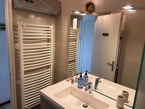 A modern bathroom with a white sink, two faucets, and a mirror. There are two bottles of hand soap and a pair of candles on the sink. - Plage de Canet T3 (Canet-en-Roussillon)