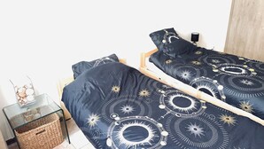Ett sovrum med två sängar, var och en med ett mörkblått sängöverkast med cirkelformade mönster. Bredvid sängarna står ett litet glasbord och en flätad korg.