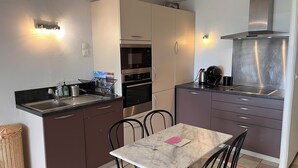 Ett kompakt kök med diskho, spis, ugn och en matplats med bord och stolar.