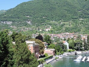 A coastal town with a marina, historic buildings, and lush green hills in the background. - The View Lake Como by Interhome (Tremezzina)