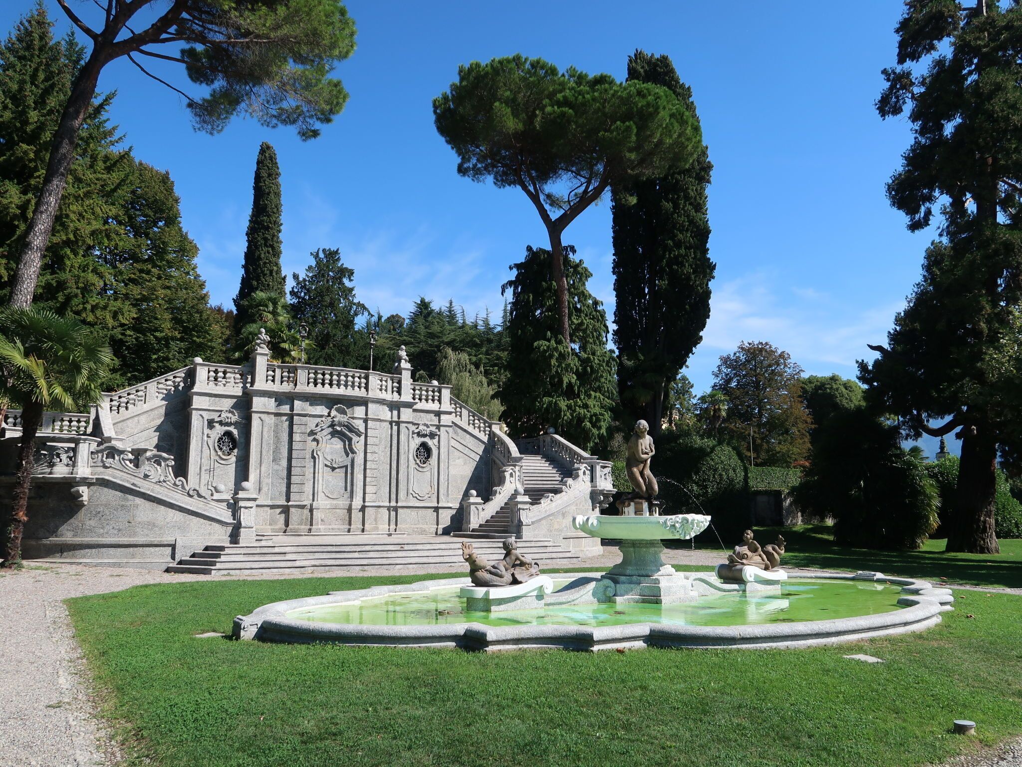 Un giardino all'italiana con una fontana, scalini in pietra e statue.