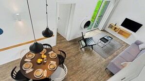Un soggiorno moderno con zona pranzo, divano, TV e vista sull'esterno.