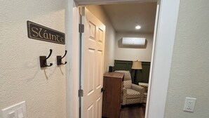 Un pasillo con una puerta blanca, un cartel que dice "Sláinte", un perchero y una pequeña mesa con una lámpara.