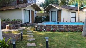 Une maison à deux étages avec une piscine, un chemin de pierre et un jardin fleuri.