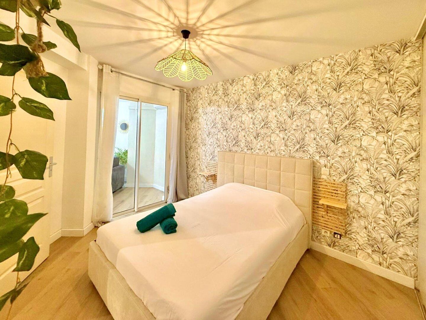 A bedroom with a bed, a ceiling light, a window, and a door.