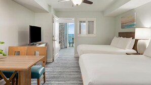 A hotel room with a TV, a desk, two beds, a balcony with a view, and a ceiling fan. - 1 bdrm oceanfront resort (North Myrtle Beach)