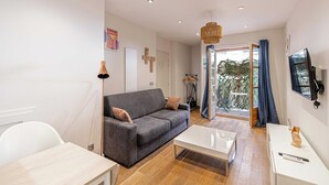 Ein modernes Wohnzimmer mit grauem Sofa, einem weißen Couchtisch und einem Fernseher an der Wand.