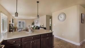 A kitchen with a large island, dark wood cabinets, pendant lights, and a wall clock.