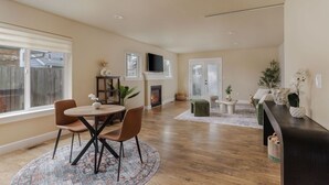 A spacious living room with a fireplace, a dining area with a round table and chairs, and a kitchen counter.