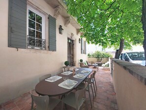 An outdoor patio with a dining table set for four, surrounded by chairs, a small potted plant, and a stone wall. - L ancien Hôtel Creste by Interhome (Banon)