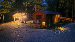 En hytte med træfacade, veranda og en overdækket område med lys.