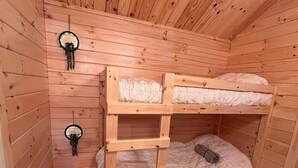 Et værelse med køjesenge i træ, skråvæg og to spejle monteret på væggen.