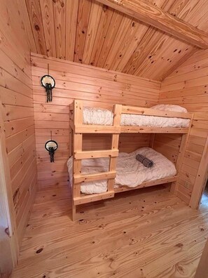 Habitación con literas de madera, techo inclinado y dos espejos fijos a la pared.