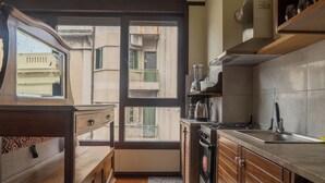 A compact kitchen with a window, wooden cabinets, a stove, and a sink. - Taylor's Port [3] Landing in the Old Town (Montevideo)