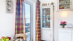 Een keuken met een eettafel, een kast met glazen deuren en uitzicht op het buitengebied.