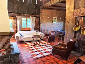 A rustic room with a bed, a sofa, a coffee table, and a fireplace.