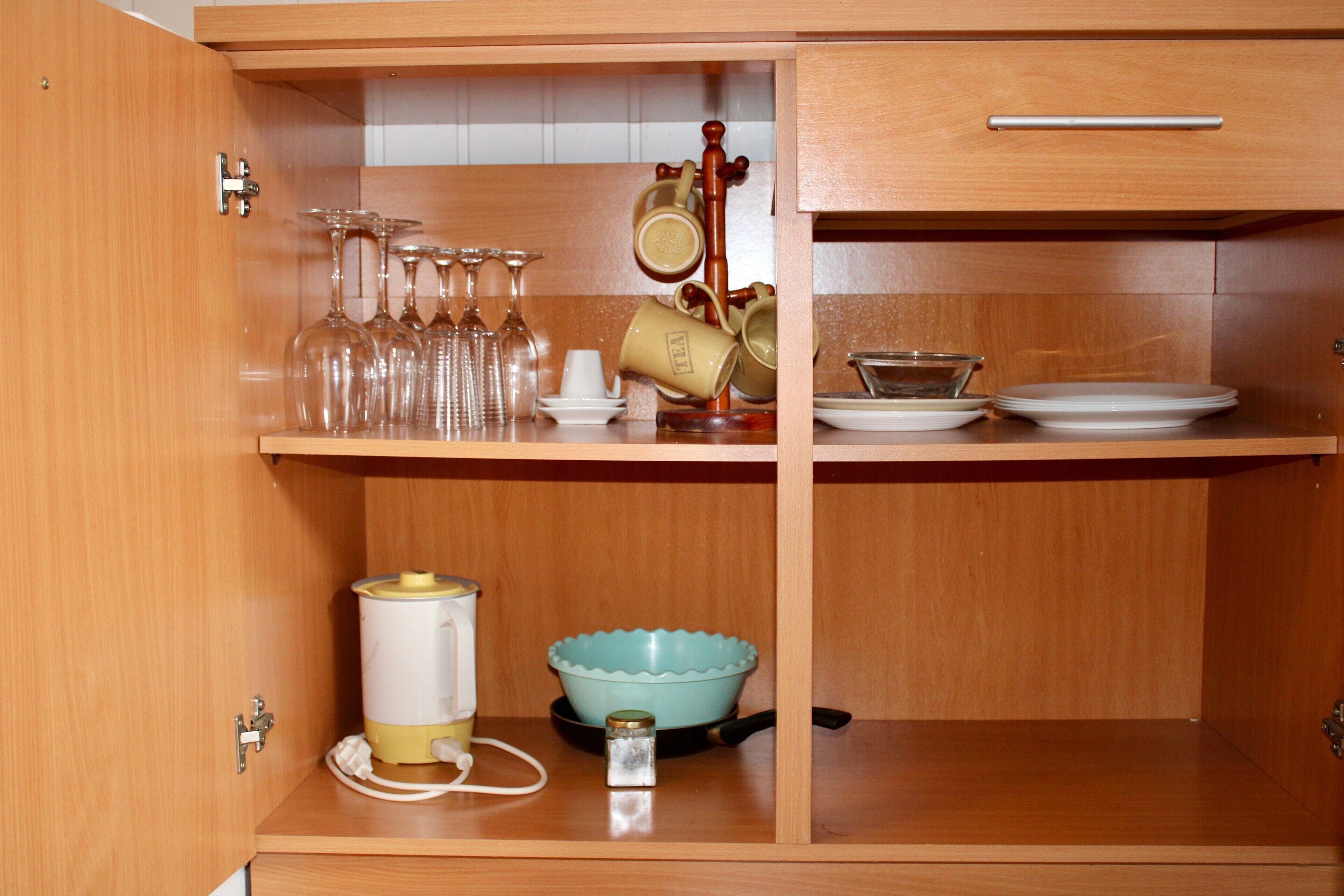 A kitchen with wooden cabinets, a coffee maker, a tea kettle, a blue bowl, and a wine rack.