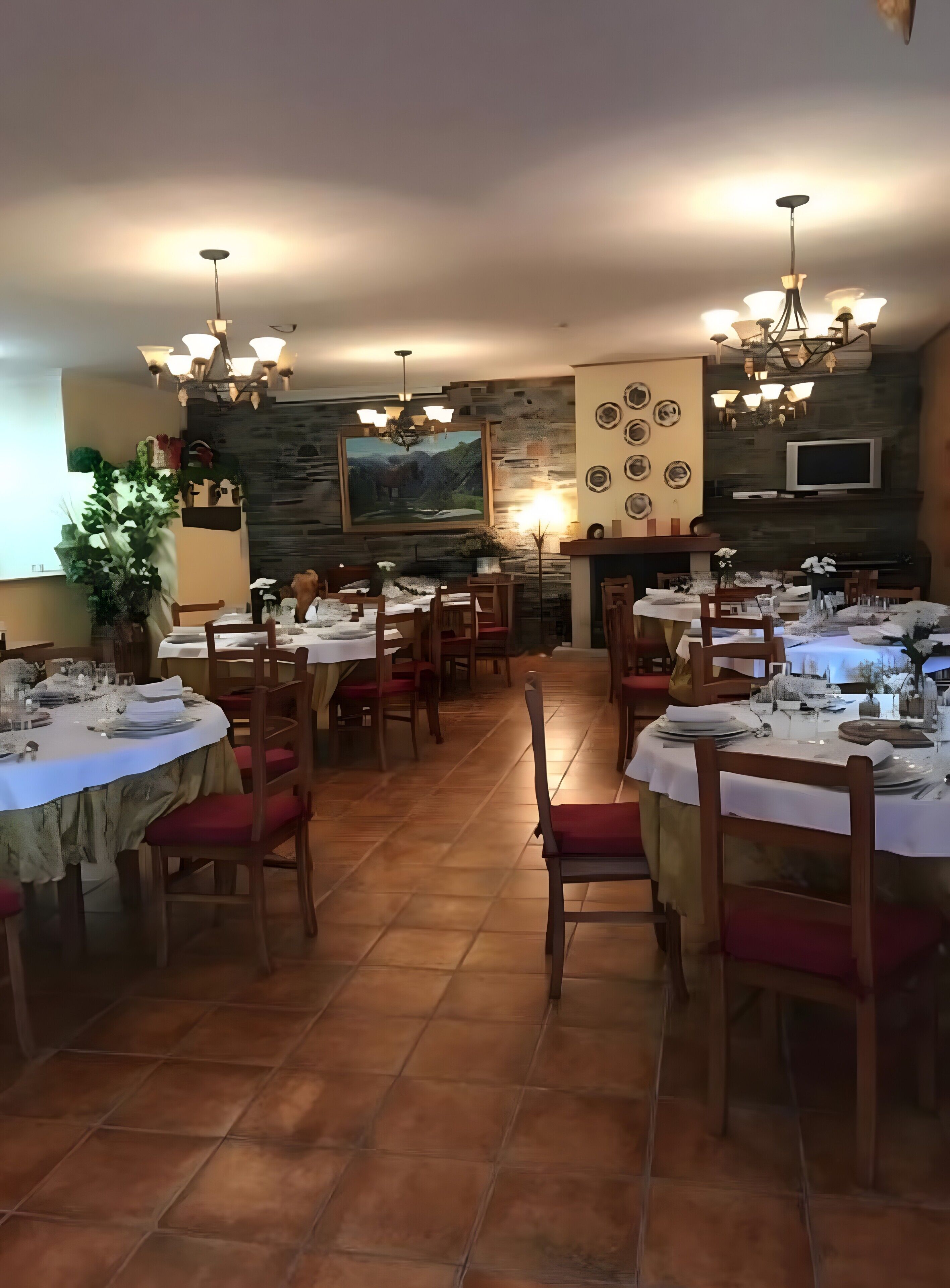 A dining area with multiple tables, chairs, and a stone wall with a painting.