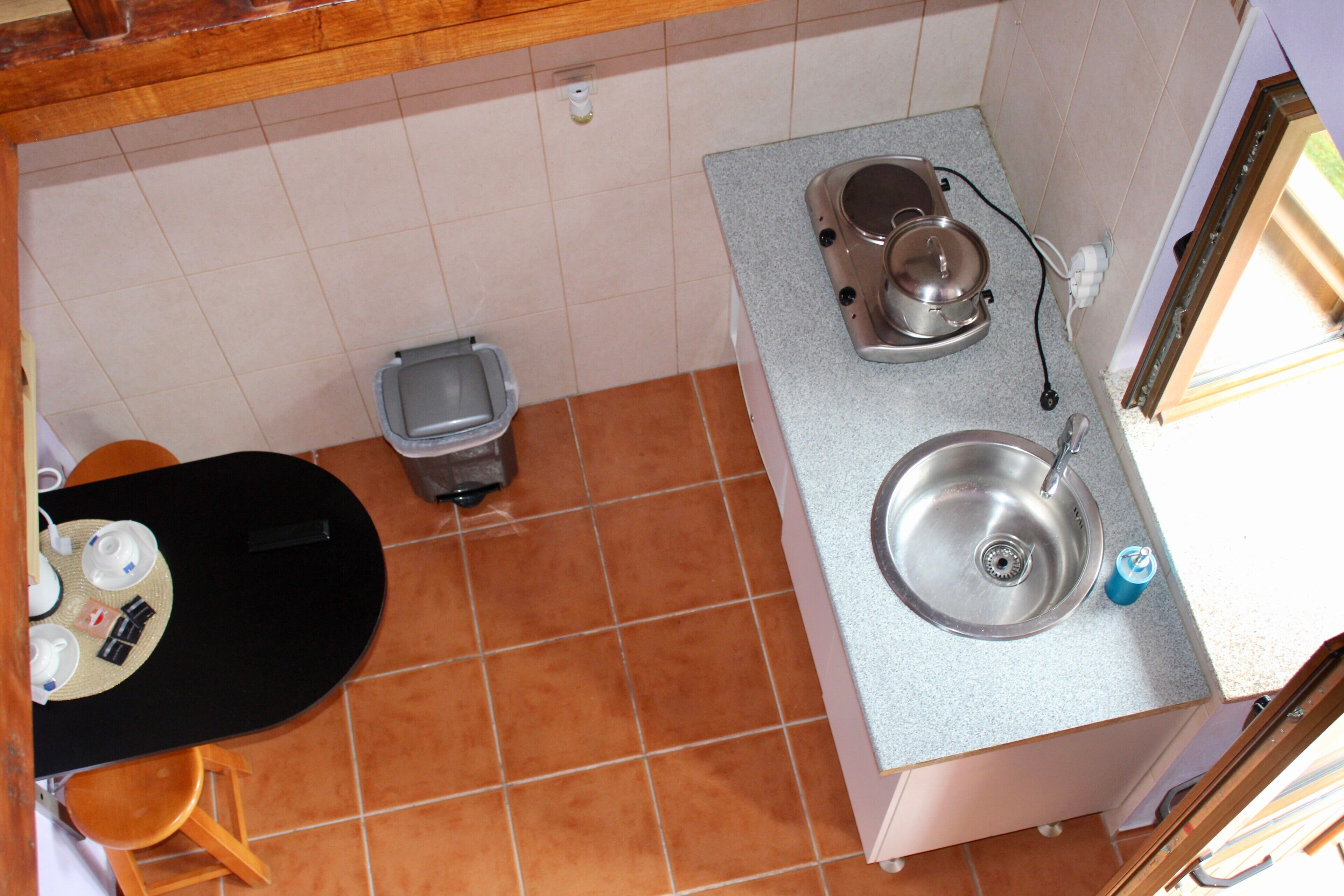 Una cocina compacta con un lavamanos, estufa y un bote de basura.