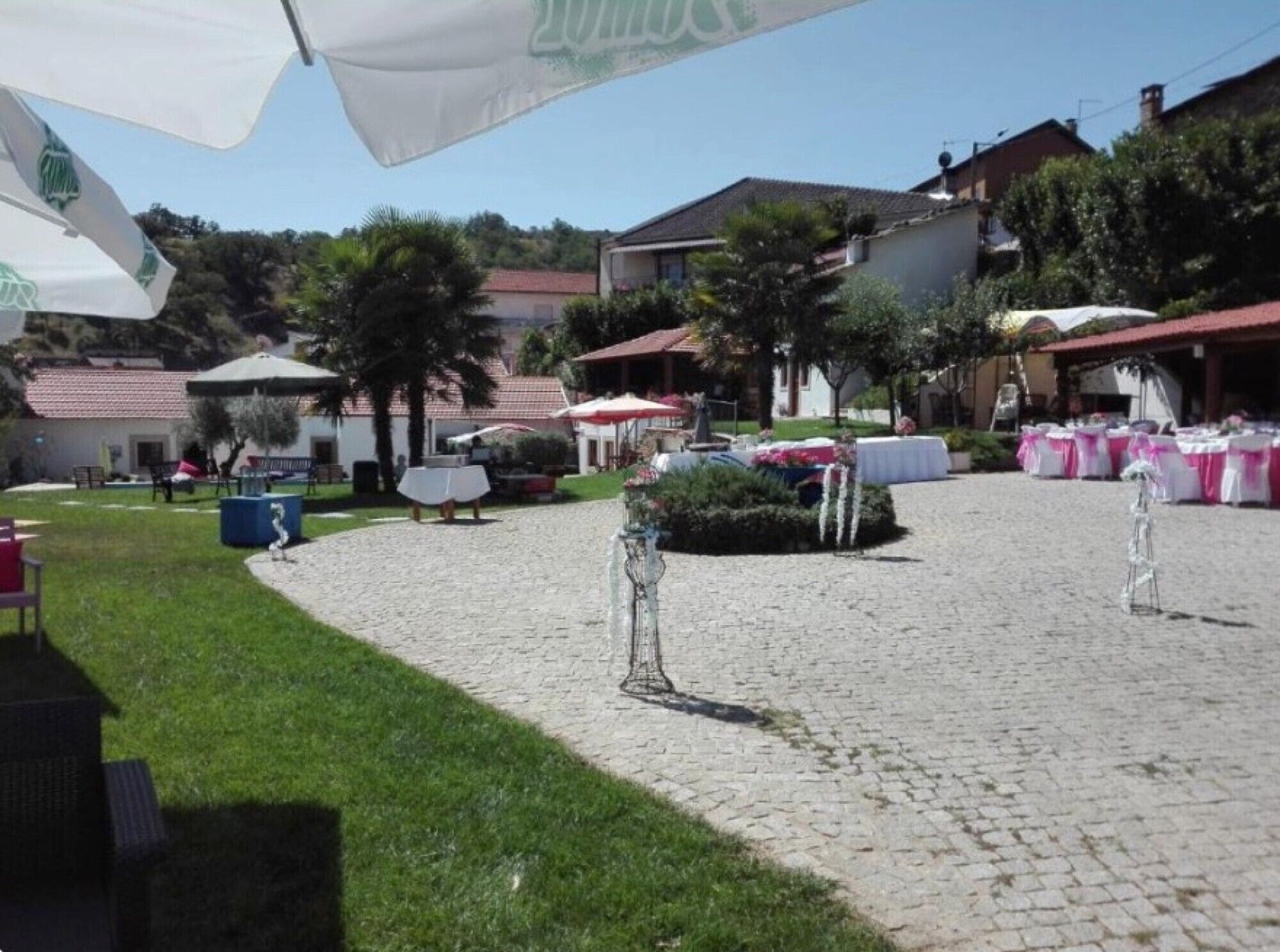 A courtyard with cobblestone flooring, outdoor tables, and umbrellas.