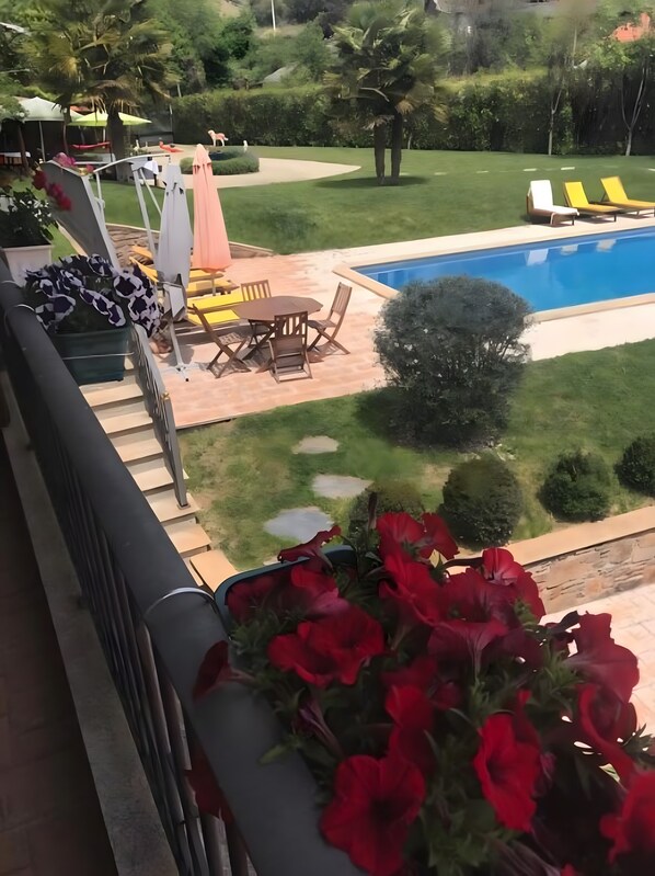 Zona junto a la piscina con una mesa y sillas, un pequeño jardín y vistas a la piscina.
