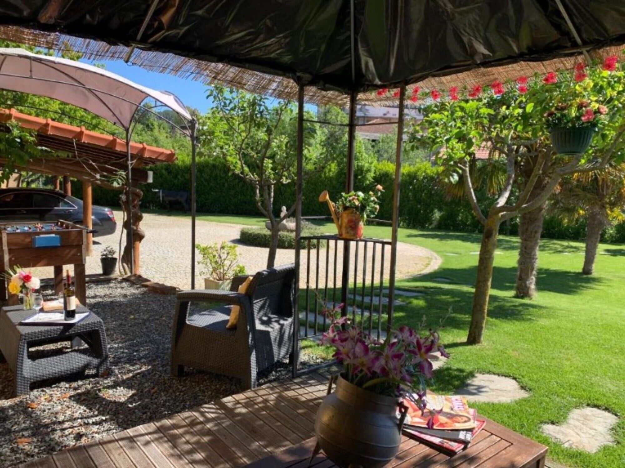Un patio al aire libre con zona de estar cubierta, una parrilla y vistas a un jardín.