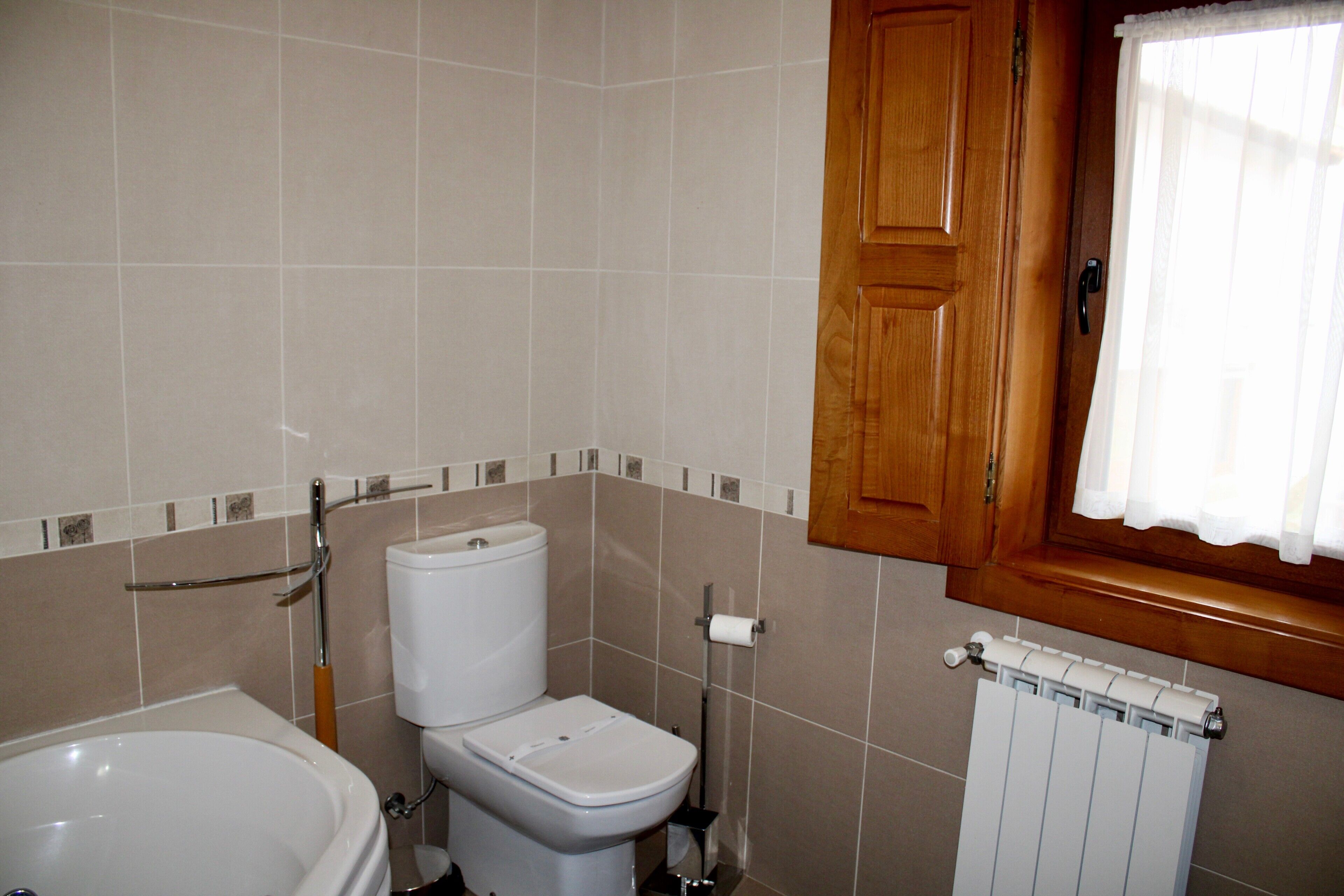 Ein Badezimmer mit Badewanne, Toilette und Heizkörper.