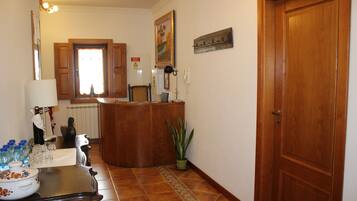 Una cocina con armarios de madera, suelo de baldosas, una planta en maceta y una puerta.